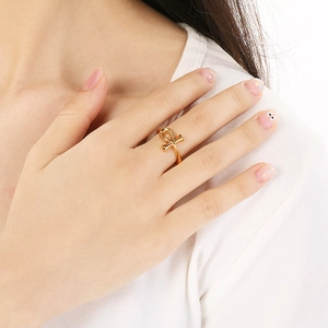 Dettaglio dell'anello con croce Ankh dorata sulla mano dal design minimalista e lucido