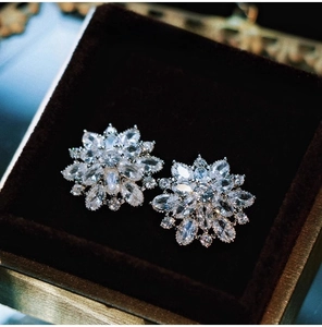 Macro shot of silver snowflake earrings with cubic zirconia on black velvet background