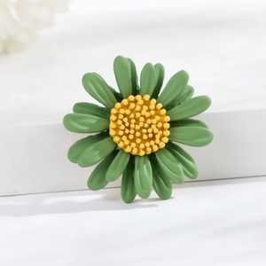 Detailed macro view of green daisy brooch featuring yellow center and matte texture