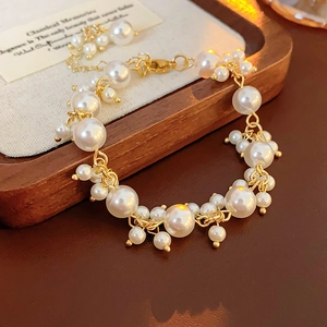 Detail of elegant pearl bracelet with gold alloy chain on a wooden display tray