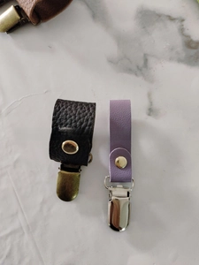 Detailansicht der hochwertigen Leder-Hutclips in Schwarz und Lavendel mit Metalldruckknopf
