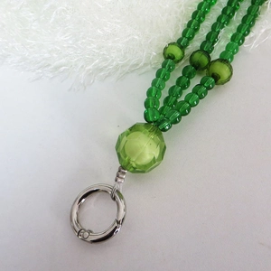 Detail shot of a clear emerald green beaded handbag strap with a silver metal spring clasp