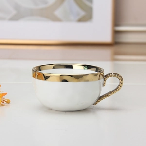 Detail of white ceramic cup with luxury gold beaded handle and elegant gilded rim finish