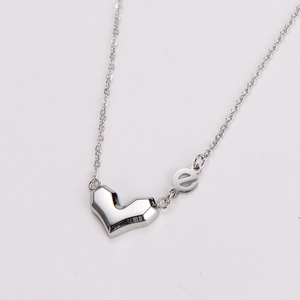 Macro view of silver geometric heart pendant and letter e detail on necklace chain