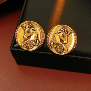 Macro view of vintage gold unicorn earrings with purple rhinestones and blue gem eyes