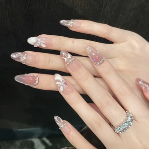 Macro detail of handmade cat eye press-on nails with 3D butterfly and rhinestone accents