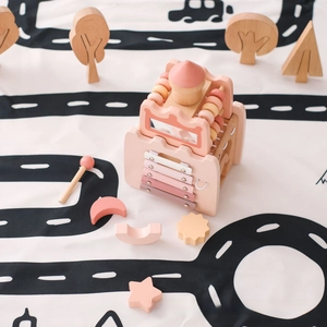 Macro detail of wooden activity house toy with pink xylophone and bead maze on play mat
