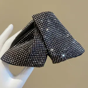 Elegant black fabric bow hair clip featuring sparkling rhinestones in a handheld view