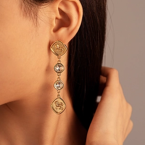 Detail of vintage gold rectangular chain earrings with lion coin and clear crystal stones