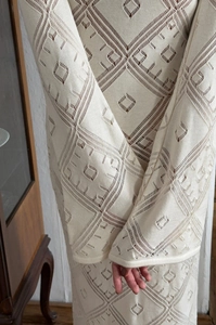 Dettaglio dell'abito in maglia beige con motivi geometrici traforati
