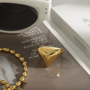 Polierter goldener Dreiecksring mit Hochglanz-Finish auf stilvollem Magazinhintergrund