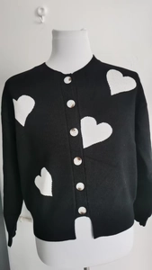 Detail of black knit cardigan with white heart patterns and five-button round neck closure