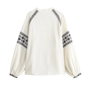 Boho ivory embroidered blouse with lantern sleeves and black ethnic patterns on white background