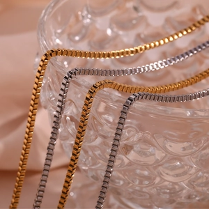 Classic 18K gold and silver stainless steel box chain necklace on luxury glass base