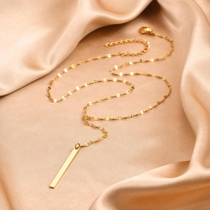 Minimalist gold bar pendant necklace with cubic zirconia tassel on silky background