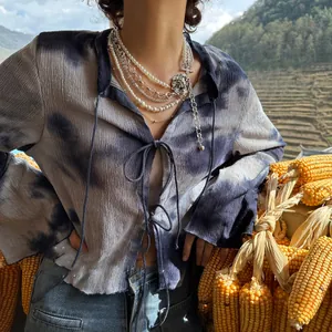 Detail of layered pearl and silver chain necklace with vintage pendant on tie-dye shirt