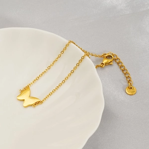 Elegant gold butterfly charm bracelet in stainless steel for women on white ceramic plate