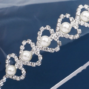 Elegant silver heart-shaped pearl headband with sparkling rhinestones on blue fabric