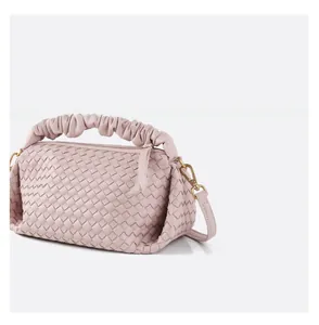 Detail of light pink woven handbag featuring ruffled handle and gold metal hook