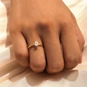 Close-up of a pear-shaped diamond ring in gold finish on a champagne silk background