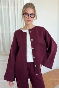 Close-up of burgundy knit cardigan featuring distinctive marble buttons and soft texture