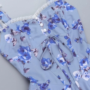 Detail des blauen Blumenkleides mit weißem Spitzenbesatz und dekorativen Knöpfen