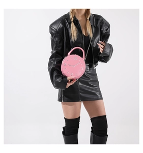 Détail d'un sac à main rose en forme d'horloge avec cadran et chaîne en métal argenté