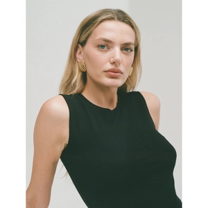 Detail showing wave textured 18K gold earrings on a model with a black top
