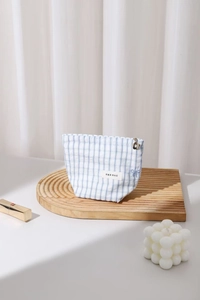 Dettaglio trousse a quadretti celeste con cerniera a fiore dorato e piccolo fiocco blu