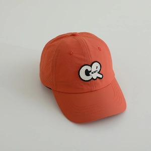 Détail du tissu respirant perforé et de l'écusson brodé sur la casquette orange