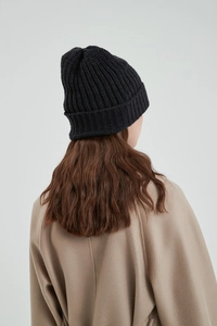 Close-up back view of a minimalist black knitted beanie showing fit and soft texture