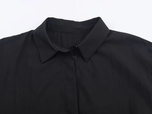 Detail of the black poplin shirt collar and button-down front with fine fabric texture