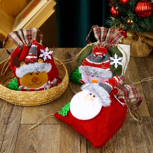 Christmas non-woven gift bags with Santa Snowman Reindeer designs on wooden table