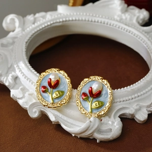 Detailed view of vintage gold flower earrings with blue enamel and pearls on a frame