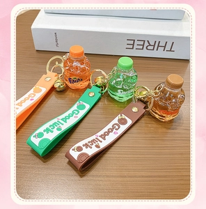 Close-up of creative liquid soda bottle keychains with silicone straps on a wooden table