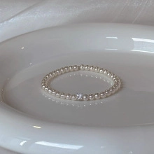 Detailed macro view of white freshwater pearls and a sparkling zircon on a minimalist bracelet