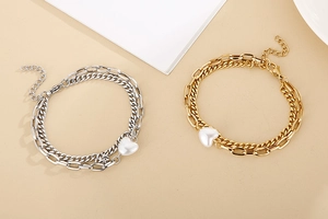 Close-up of gold and silver double-layer heart shell bracelets on beige background