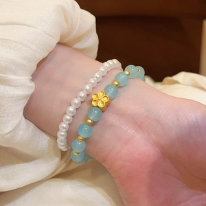 Detalle de pulsera de piedras naturales de estilo chino con dije de flor dorada
