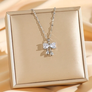Titanium steel bowknot necklace with sparkling zircons on a gold silk background
