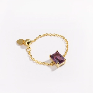 Macro view of adjustable gold chain ring with square purple zircon and heart charm