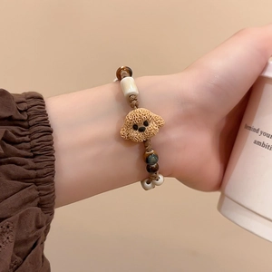 Detailed macro view of handmade braided bracelet with a cute poodle pendant and tiger eye beads
