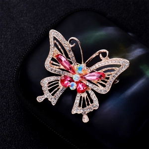 Detailed close-up of a golden butterfly brooch with pink gemstones and sparkling crystals