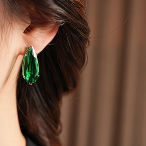 Close-up of teardrop emerald green crystal earrings with silver-tone faceted stone detail