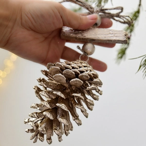 Rustic Christmas pine cone ornament with gold glitter coating and wooden block accent