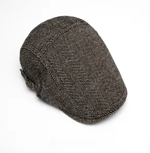 Close-up of herringbone tweed flat cap showing textured fabric and side metal buckle