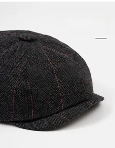 Detailed view of dark grey herringbone newsboy cap with subtle red plaid pattern
