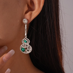 Gros plan sur un mannequin portant des boucles d'oreilles gourde en argent et émeraude