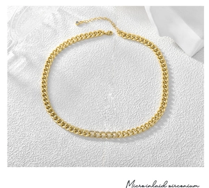 Macro view of gold plated Cuban link necklace showing zircon inlay and lobster clasp detail