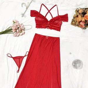 Dreiteiliges rotes Dessous-Set mit Netzrock und Spitzen-BH auf dekorativem Hintergrund