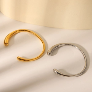 Detail of minimalist gold and silver open bangles with polished teardrop ends